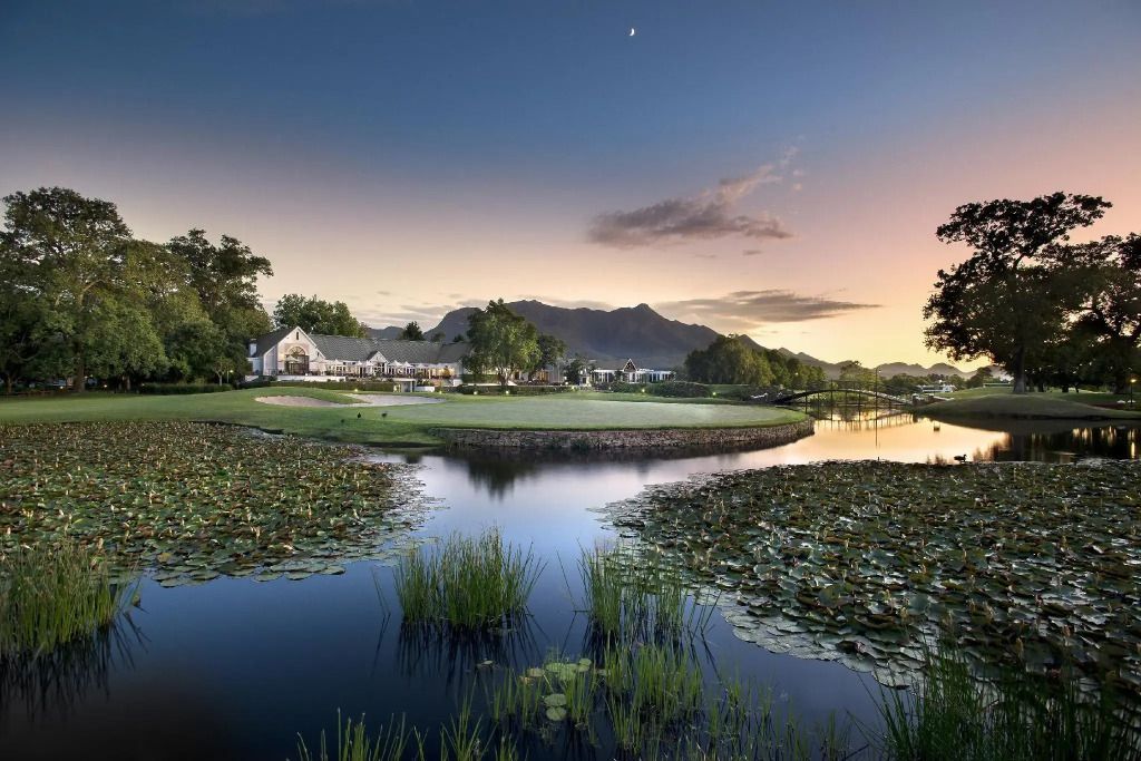 Malerische Landschaft mit einem Teich und einem Gebäude im Hintergrund bei Sonnenuntergang