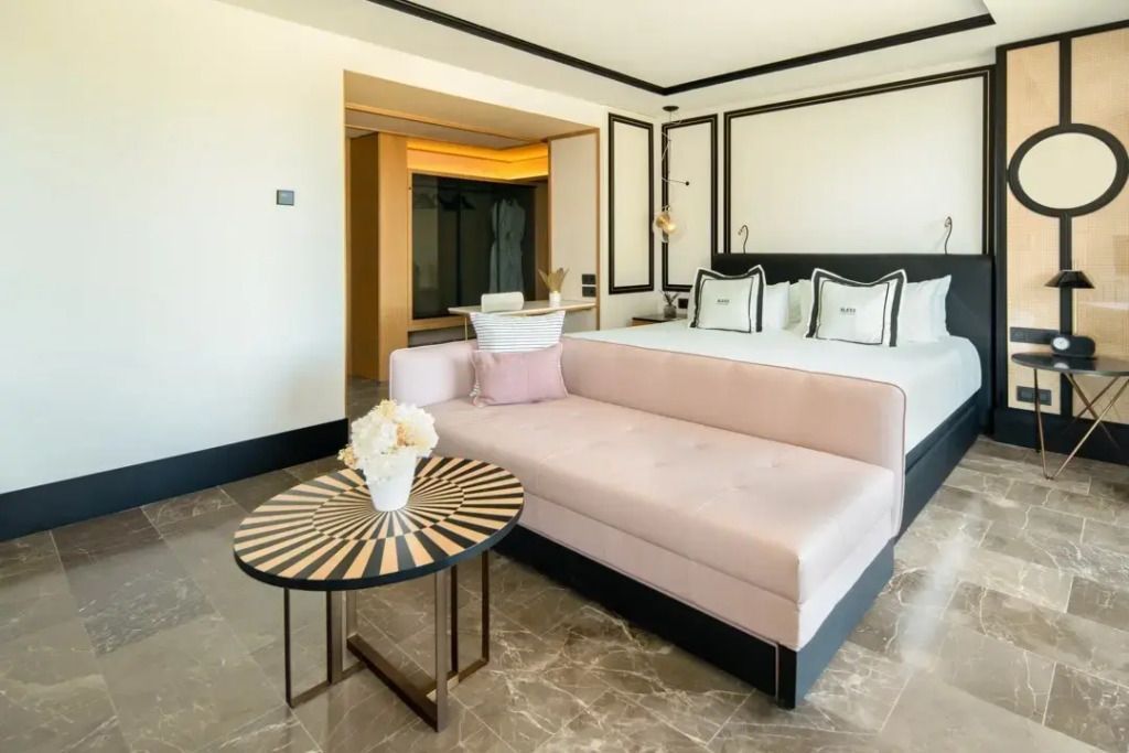 Elegante Suite mit rosa Sofa und Doppelbett mit Meerblick in heller Einrichtung