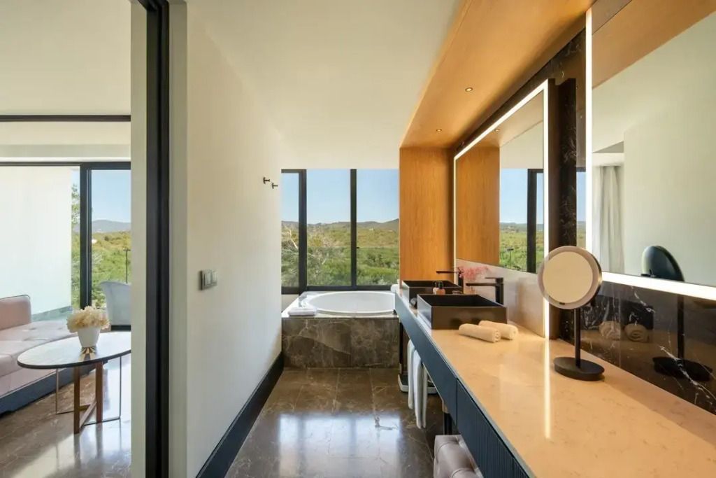 Luxuriöses Badezimmer mit großer Badewanne und Ausblick auf die Natur
