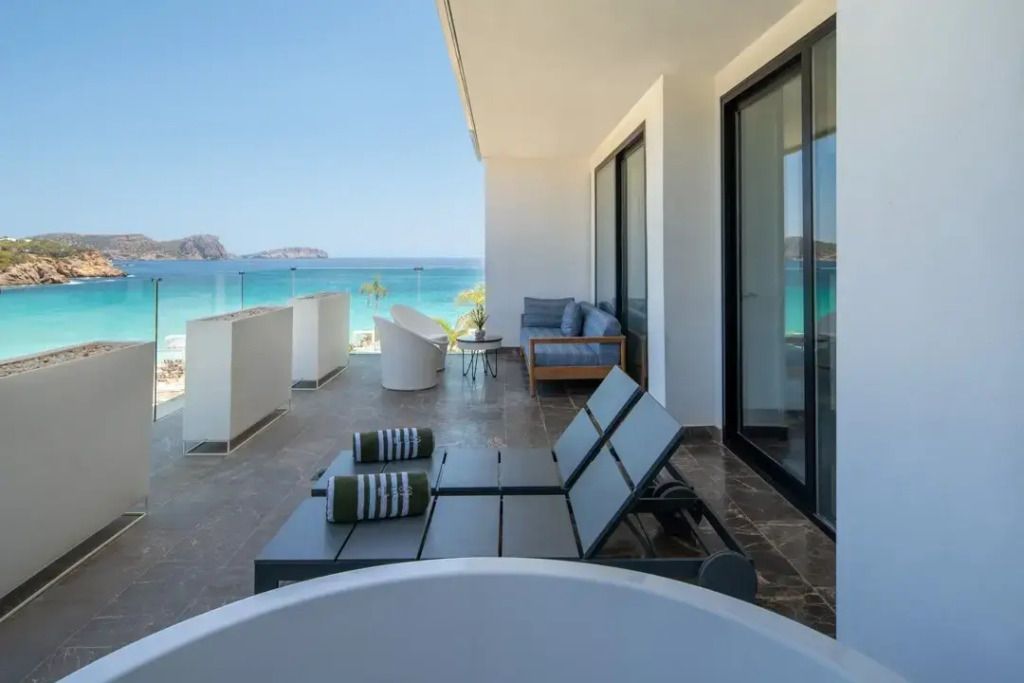 Geräumige Terrasse mit Sonnenliegen und Blick auf das Meer und die Küste