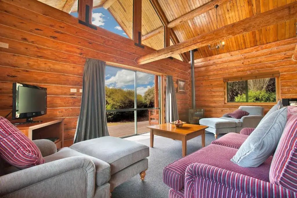 Einladendes Wohnzimmer einer Blockhütte mit großen Fenstern