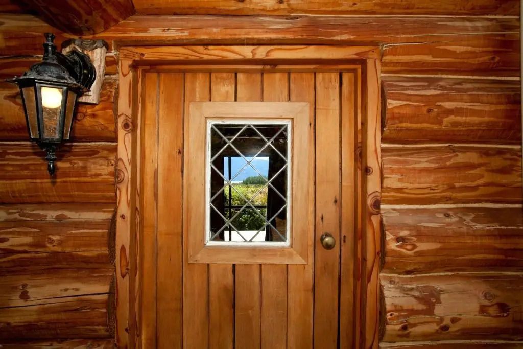 Holztür mit kleinem Fenster und Ausblick auf Landschaft