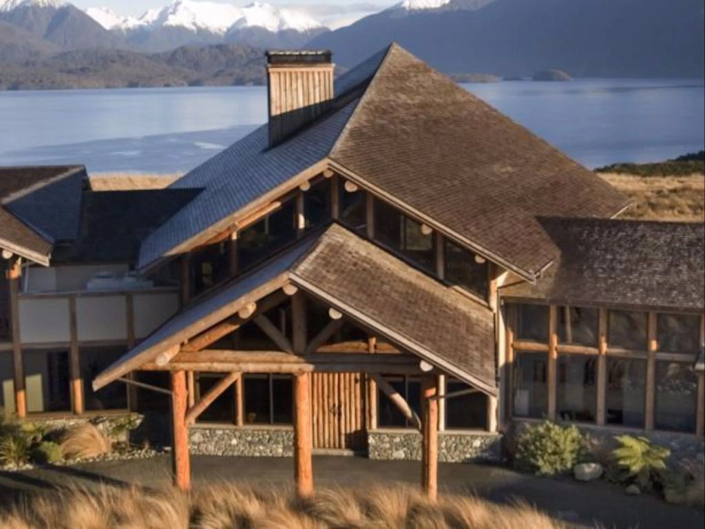 Luxuriöse Lodge mit Holzdach vor malerischer Berg- und Seekulisse