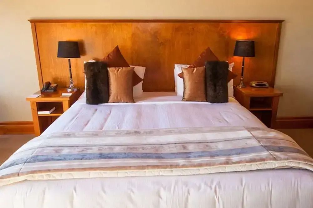 Luxuriöses Doppelbett mit eleganten Kissen in warmen Tönen.