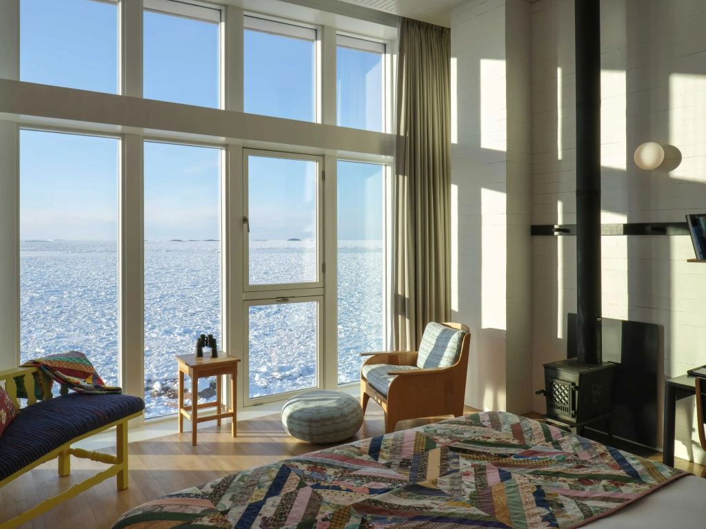 Zimmer mit Kamin und Schnee-Landschaft durch breite Fenster