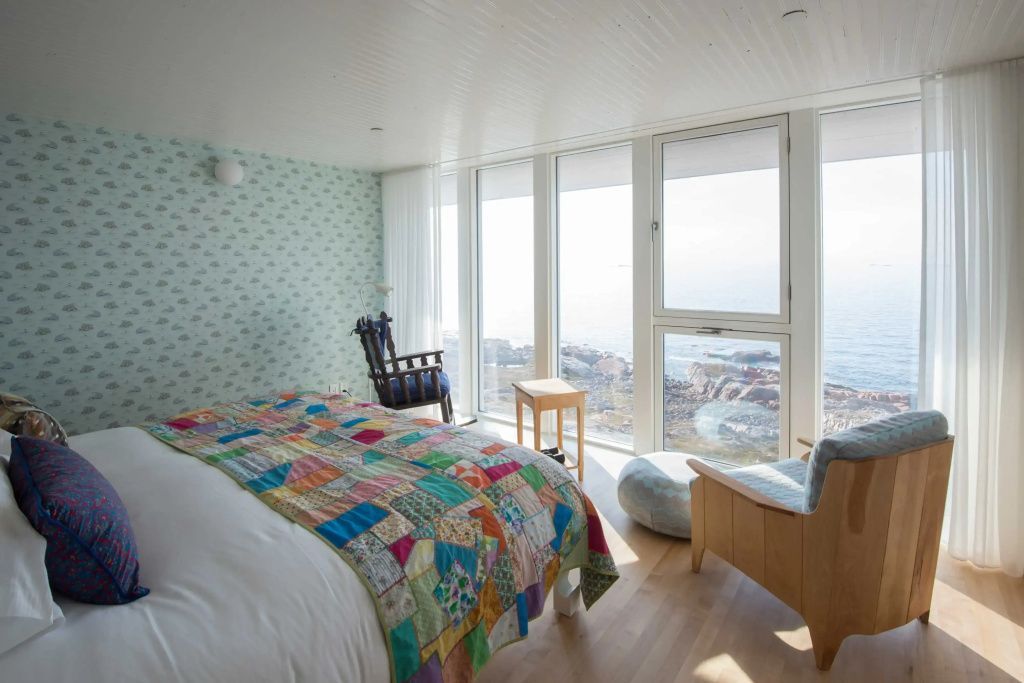 Schlafzimmer mit buntem Quilt und beeindruckendem Meerblick