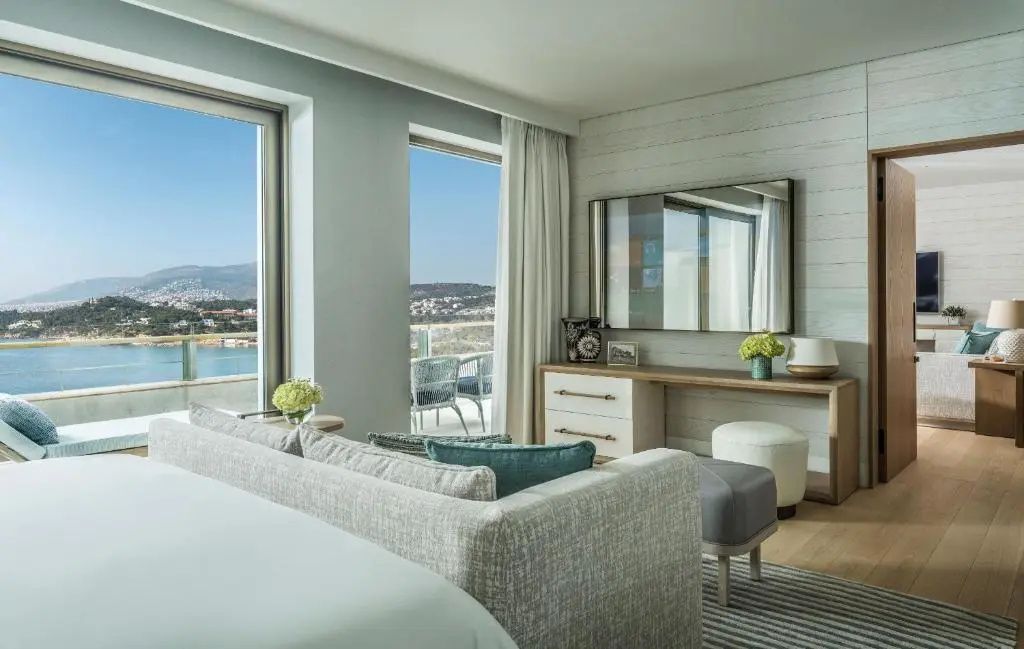 Modern eingerichtetes Schlafzimmer der Arion Suite mit Sofa, Schreibtisch und Blick auf das Meer.