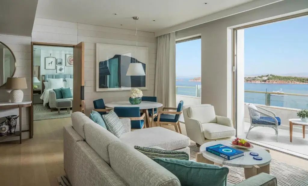 Großzügiger Wohnbereich der Arion Suite mit stilvollen Sitzmöbeln, Esstisch und Panoramablick auf das Meer.