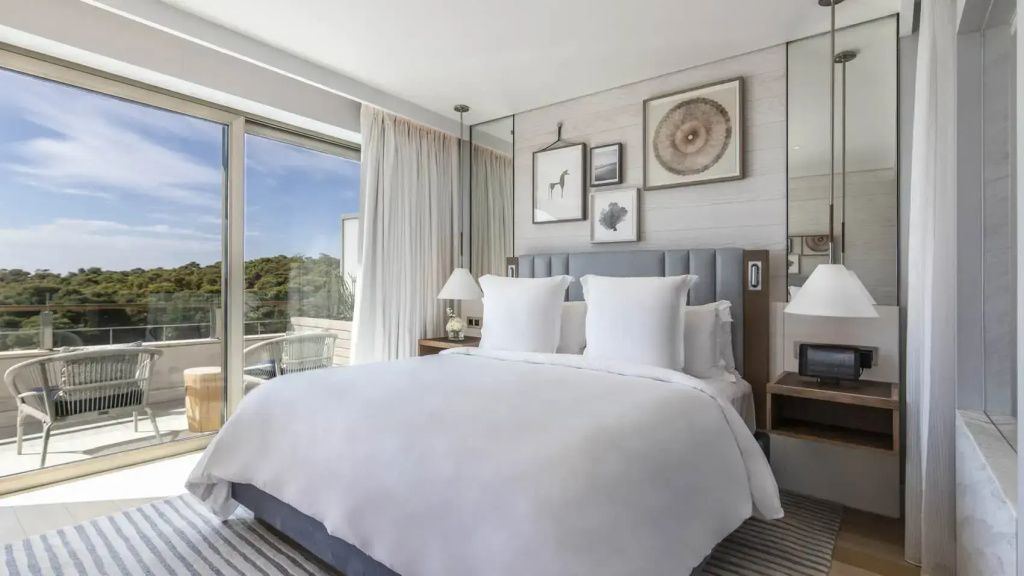 Doppelbett mit weißen Kissen in der Arion Executive Suite mit Blick ins Grüne.