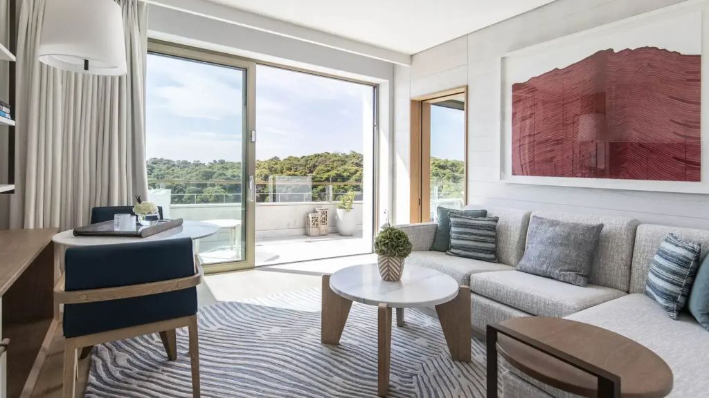 Wohnbereich der Suite mit modernem Sofa, Couchtisch und Blick auf die private Terrasse.