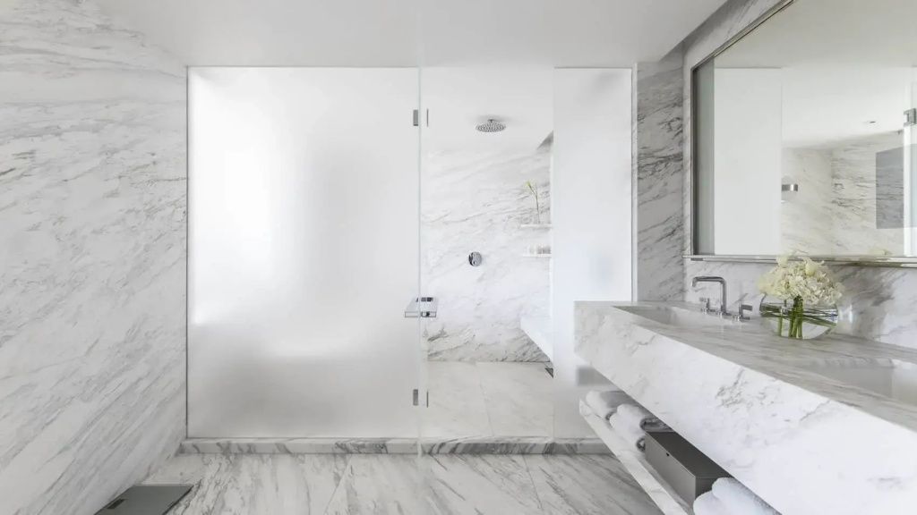 Luxuriöses Badezimmer aus weißem Marmor mit begehbarer Glasdusche und Waschtisch.