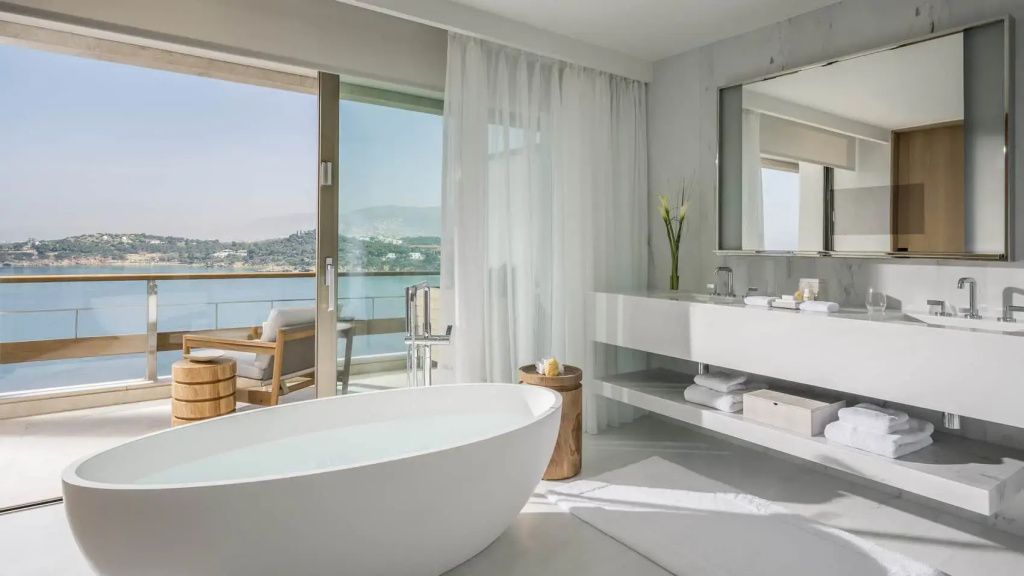 Modernes Badezimmer mit freistehender Badewanne und herrlichem Meerblick vom Balkon.