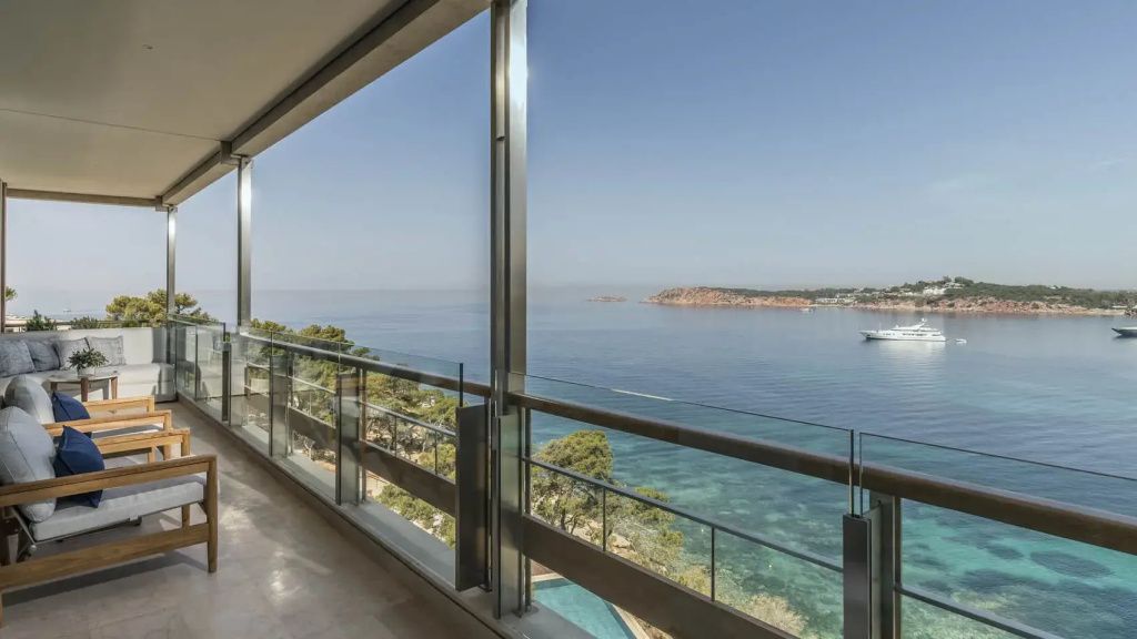 Privater Balkon mit Glasgeländer und Panoramablick auf das blaue Meer und die Küste.