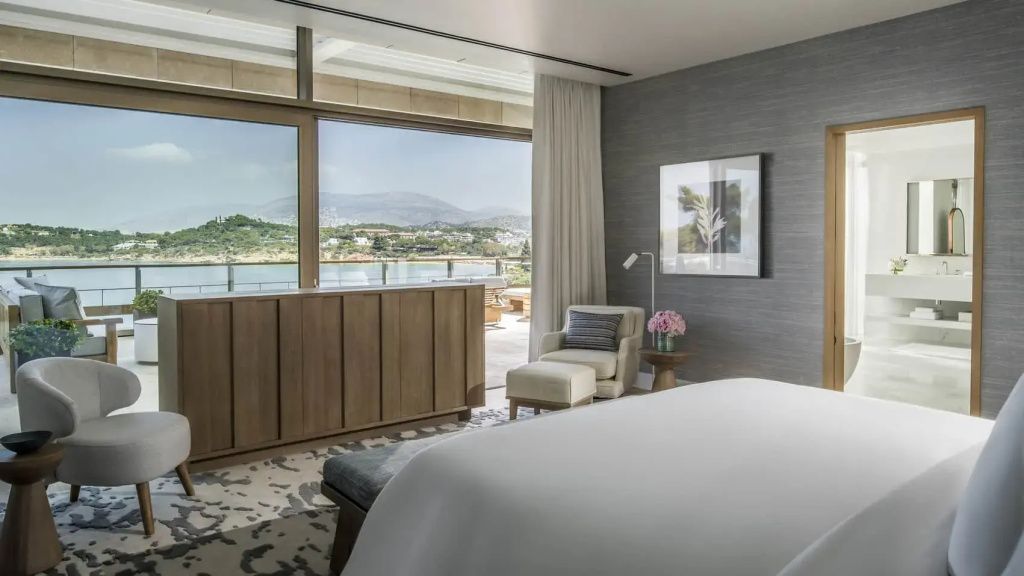 Luxuriöses Schlafzimmer der Arion Royal Suite mit gemütlichem Sessel und Zugang zur Terrasse mit Meerblick.