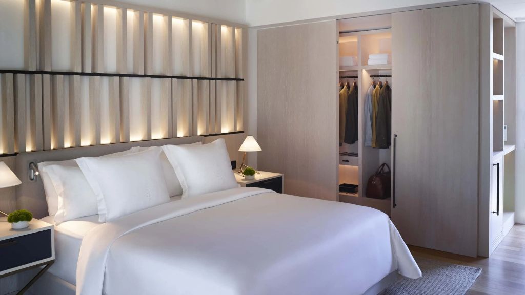 Luxuriöses Doppelbett im Bungalow mit stilvollem Kopfteil und beleuchtetem Kleiderschrank.