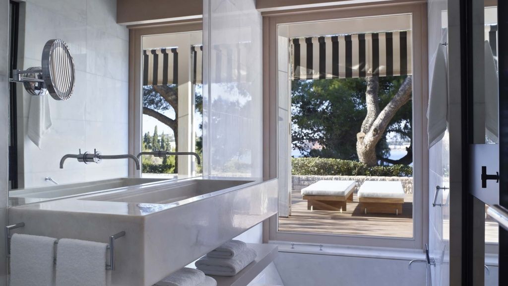 Marmor Waschtisch im Badezimmer mit Blick auf die private Terrasse und Sonnenliegen.
