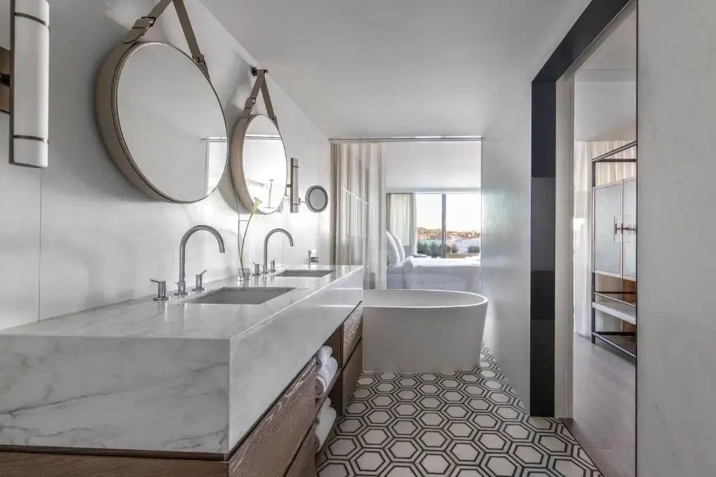 Badezimmer mit freistehender Badewanne und fließendem Übergang zum Schlafbereich mit Meerblick