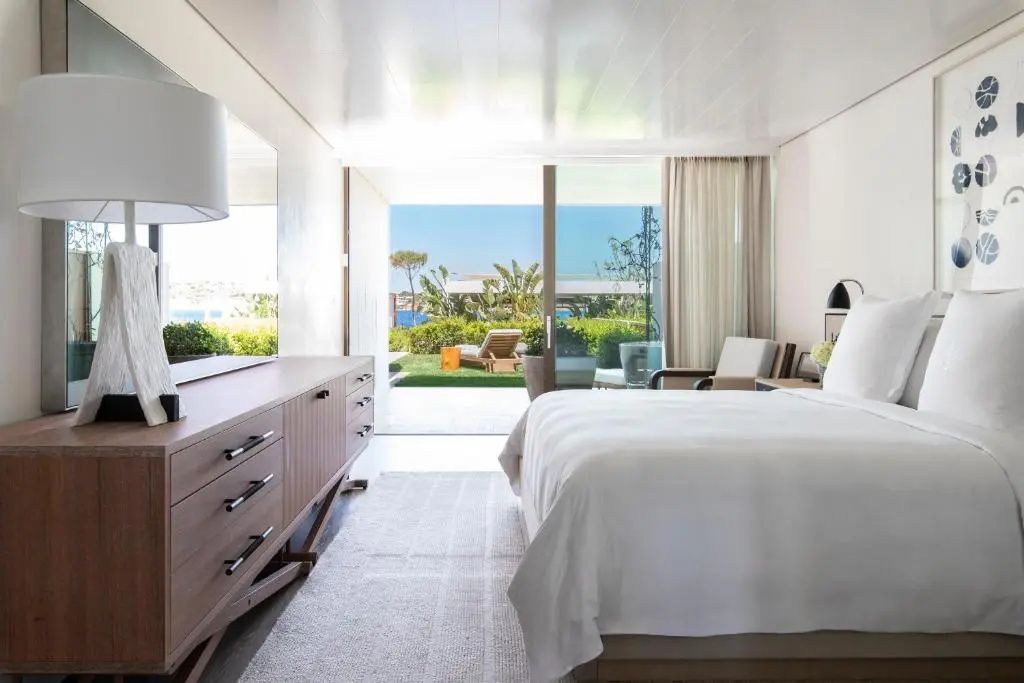 Helles Nafsika Garden Doppelzimmer mit Doppelbett und Terrasse mit Blick ins Grüne und auf das Meer.