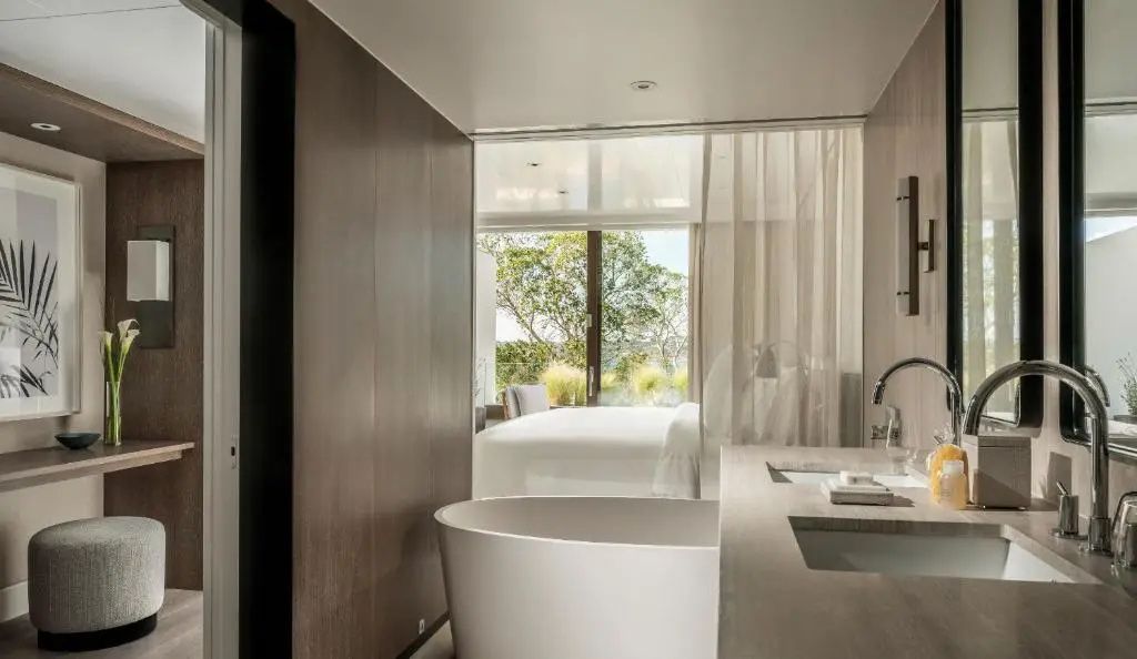 Luxuriöses Badezimmer mit freistehender Badewanne und Blick ins schicke Schlafzimmer