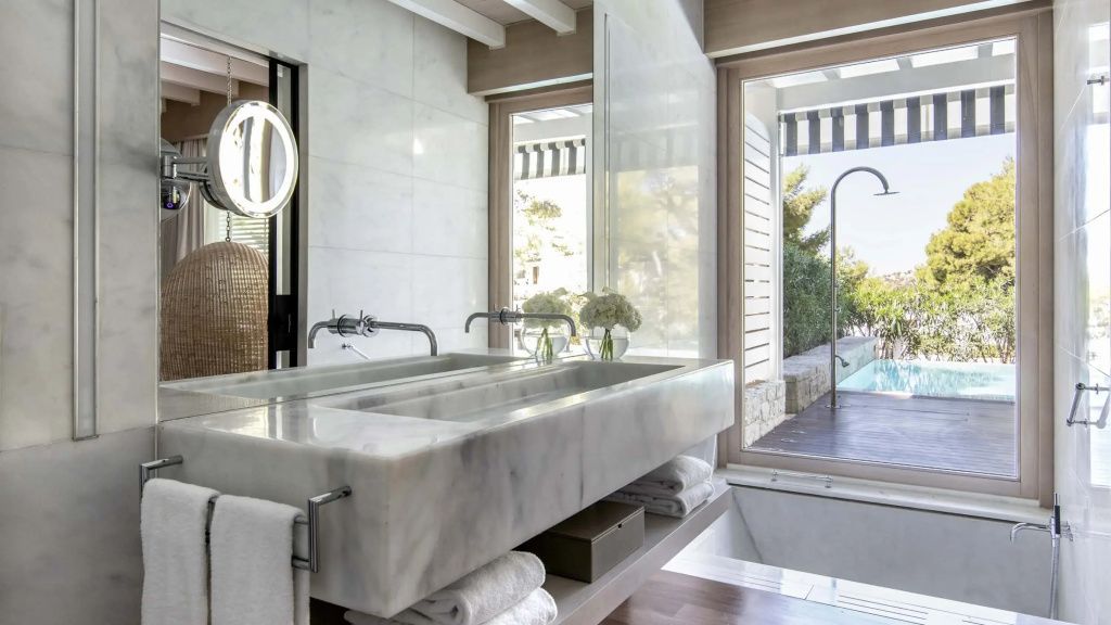 Doppelwaschbecken aus edlem Marmor im Badezimmer der Bungalow Suite mit Blick auf den Außenbereich.