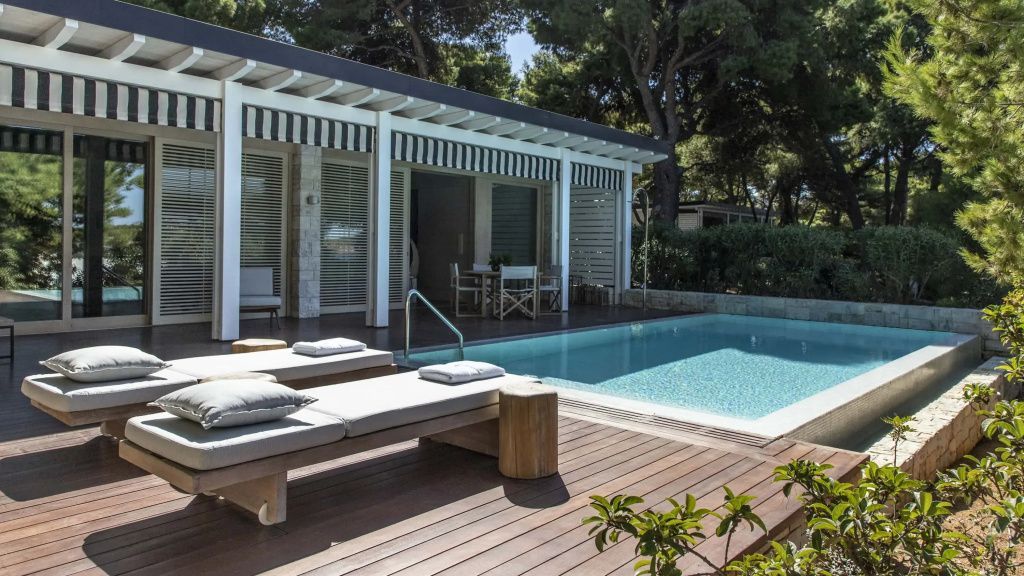 Privater Pool auf der Holzterrasse der Bungalow Suite umgeben von schattenspendenden Pinien.
