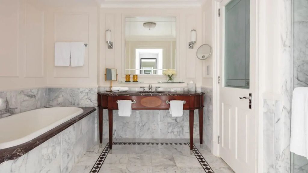 Elegantes Badezimmer mit Marmoroberflächen und großzügigem Spiegel im Hotelzimmer.