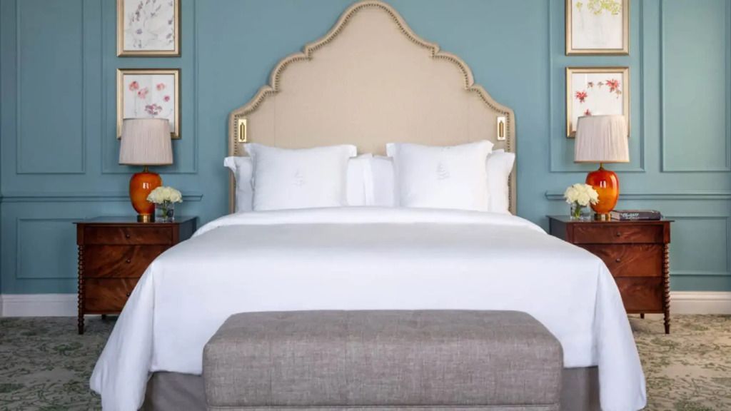 Elegantes Doppelbett mit kunstvollem Kopfteil und luxuriöser Bettwäsche