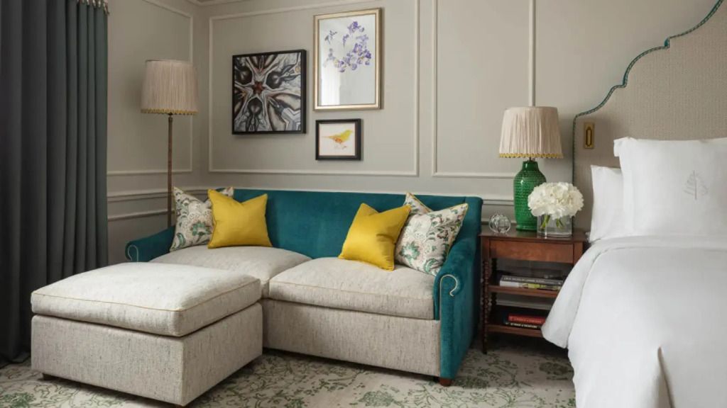 Gemütliches Sofa mit gelben Kissen und dekorativen Bildern an der Wand im Hotelzimmer