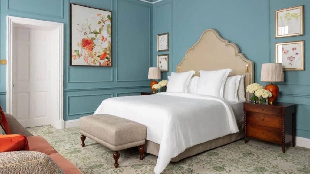 Elegantes Schlafzimmer mit blauem Wanddesign und einem großen Doppelbett mit weißer Bettwäsche.