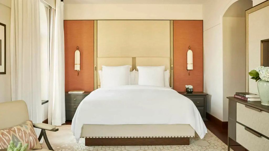 Deluxe Doppelbett mit eleganter Kopfteilgestaltung, flankiert von modernen Nachttischlampen.