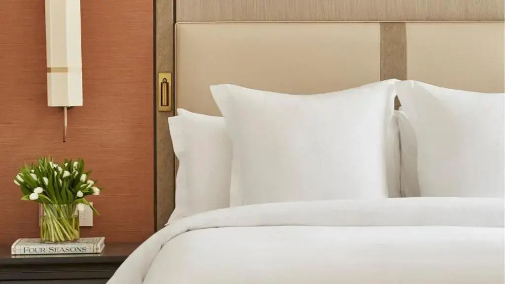 Detailaufnahme eines eleganten Hotelbetts mit weißen Kissen und Bettwäsche.