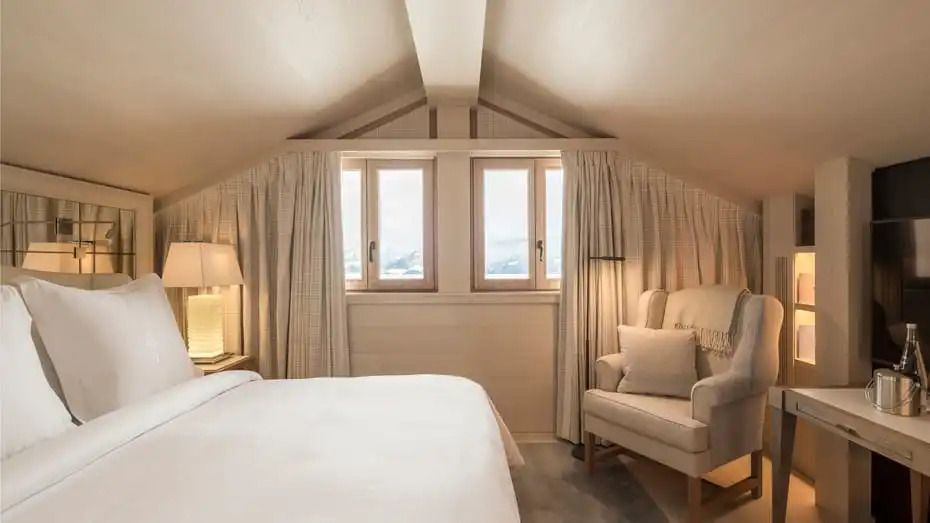 Luxuriös eingerichtetes Schlafzimmer im Dachgeschoss mit großen Fenstern und eleganten Vorhängen