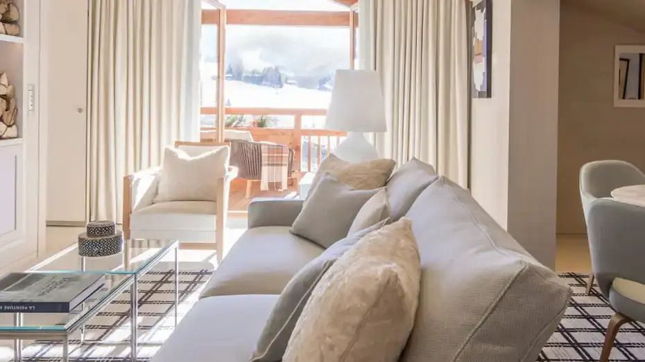 Helles Wohnzimmer mit stilvollen Sofas und Balkonaussicht auf alpine Landschaft