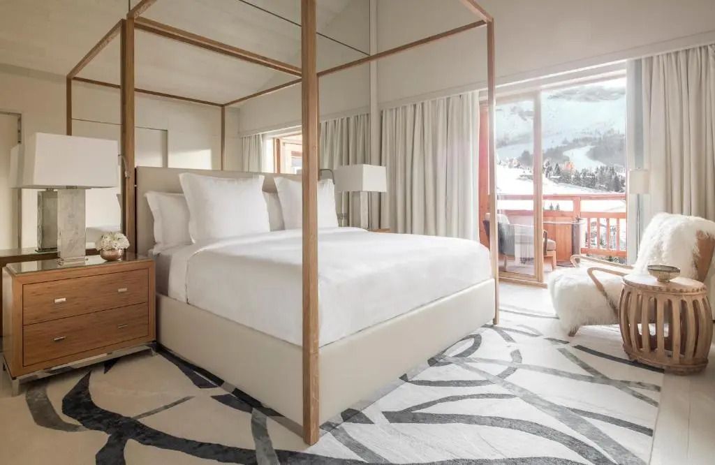Elegantes Schlafzimmer mit Himmelbett und Bergblick durch große Fenster