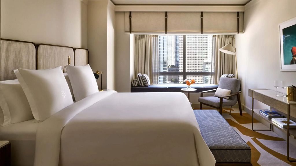 Elegantes Hotelzimmer mit Doppelbett, Stadtblick und Sitzbereich am Fenster