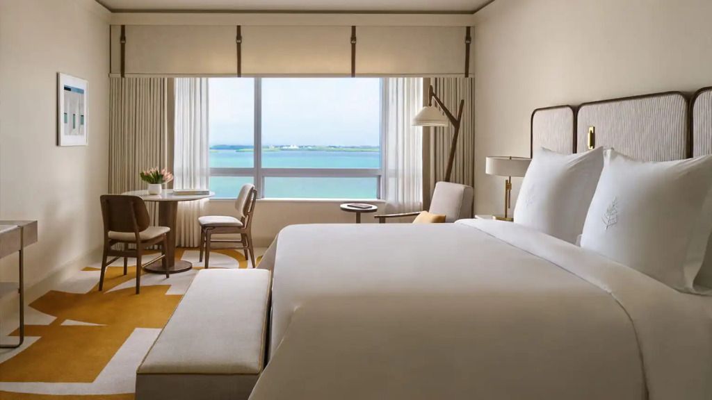Modern eingerichtetes Zimmer mit Doppelbett und Blick auf die Bucht durch ein großes Fenster