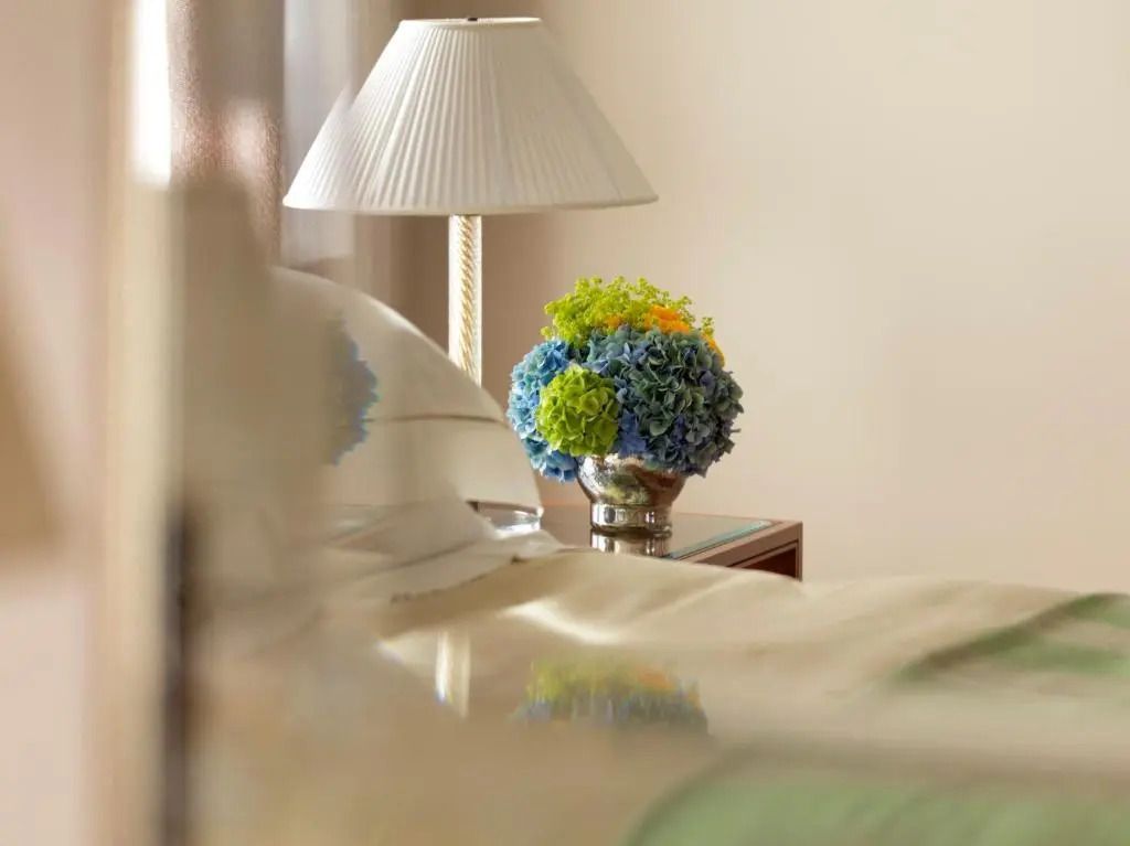 Nahaufnahme eines stilvollen Nachttisches mit blauer Blumenvase im Deluxe Doppelzimmer