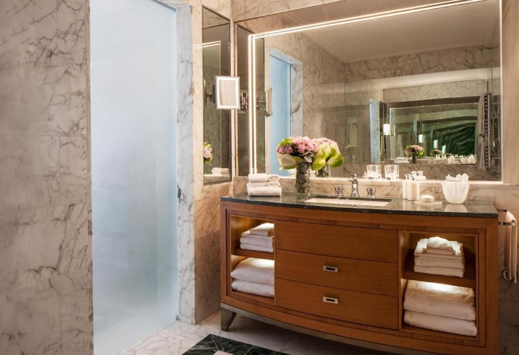 Luxuriöses Badezimmer mit Marmorwänden und Spiegelbeleuchtung im Deluxe Zimmer