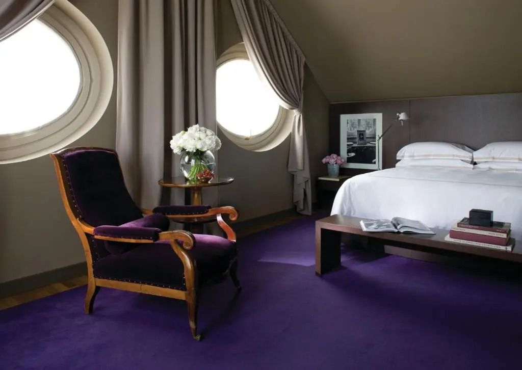 Luxuriöses Schlafzimmer mit violettem Teppich und eleganter Sitzgelegenheit