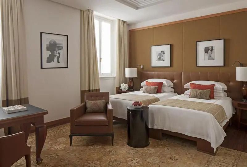 Elegantes Hotelzimmer mit zwei Einzelbetten, modernen Möbeln und stilvollen Kunstwerken.