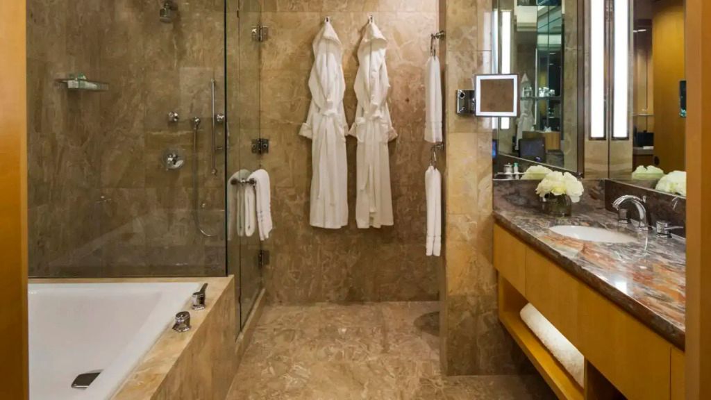Marmorbadezimmer mit Dusche, Badewanne und zwei Bademänteln