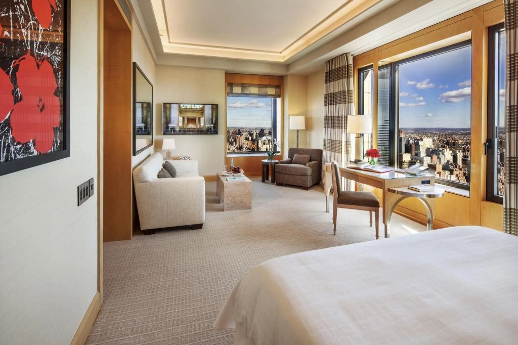 Geräumige Suite mit Doppelbett, Sofa und Blick auf die Stadt.
