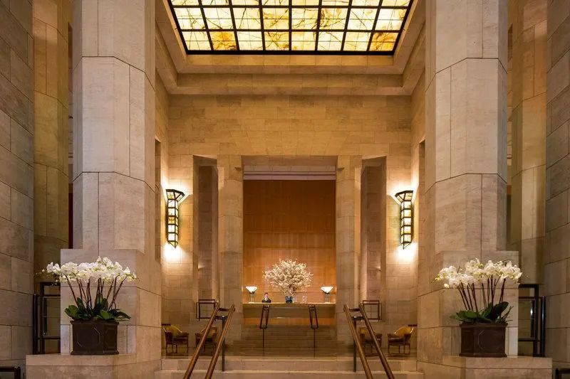 Elegante Hotellobby mit kunstvollem Glasfenster an der Decke und Orchideenarrangement