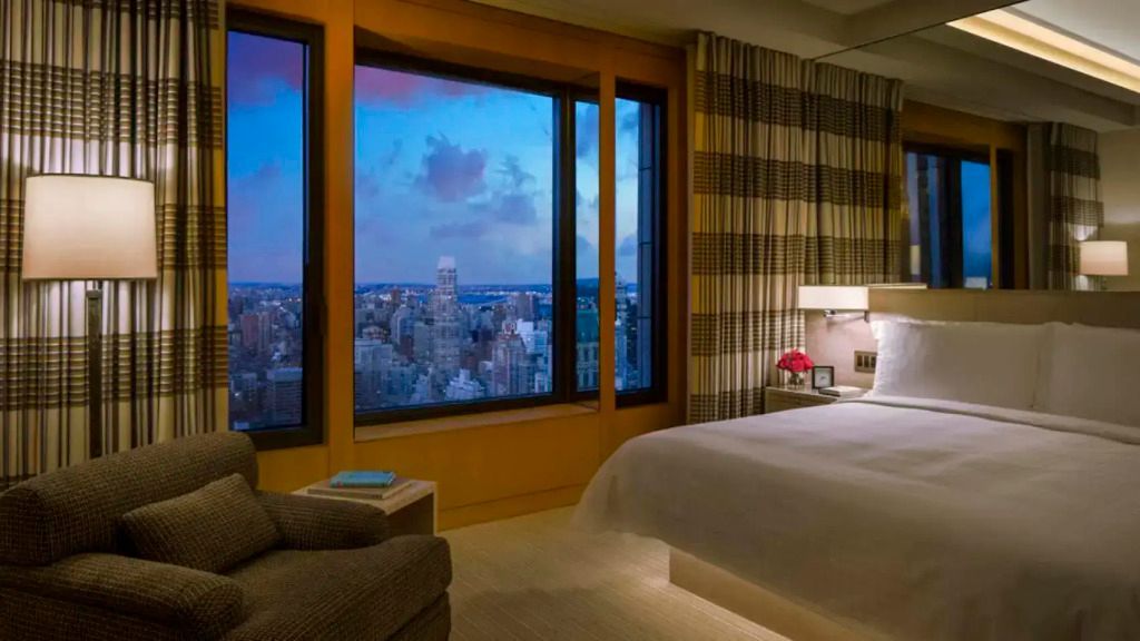 Zimmer mit großem Fenster mit Ausblick auf die Skyline von New York bei Abenddämmerung