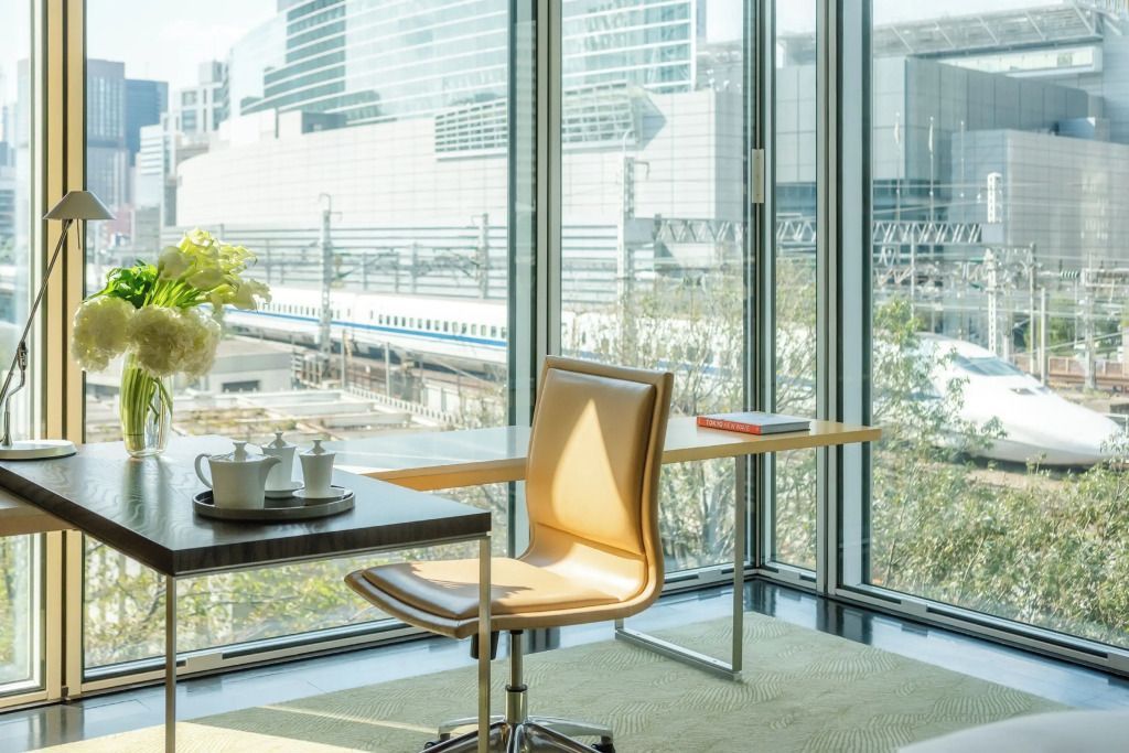 Helles Zimmer mit Schreibtisch und Stadtblick durch große Fenster im Four Seasons Hotel