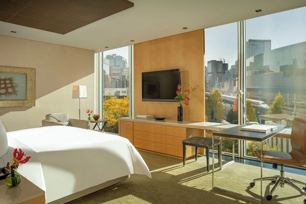 Helles Schlafzimmer mit Doppelbett und Panoramafenster im Four Seasons Tokyo.