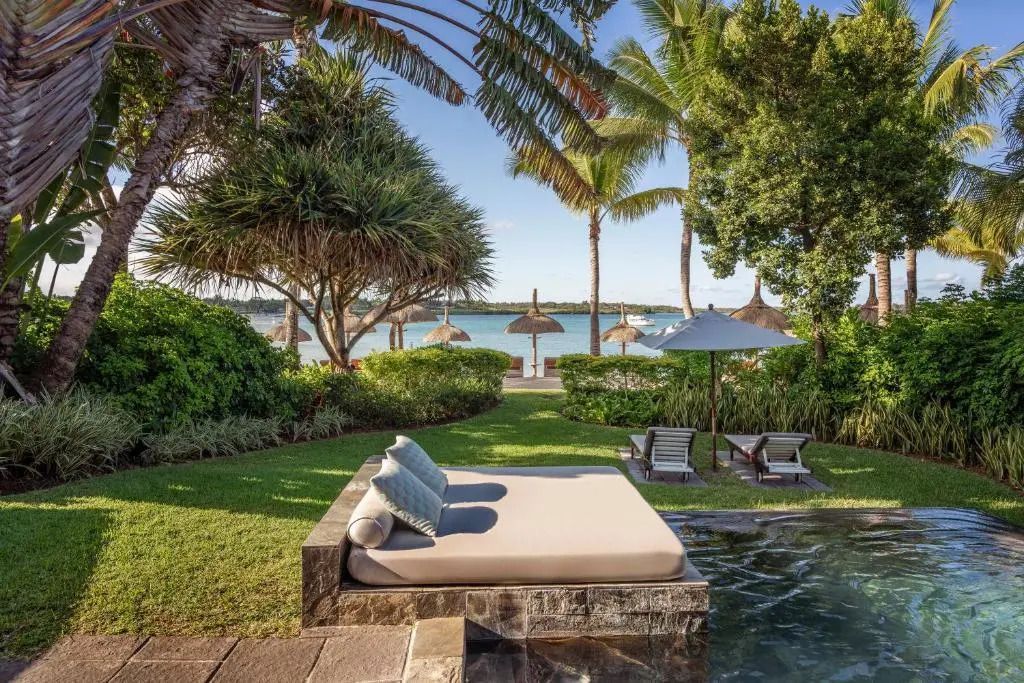 Infinity Pool mit Liegewiese und Strandblick unter Palmen.