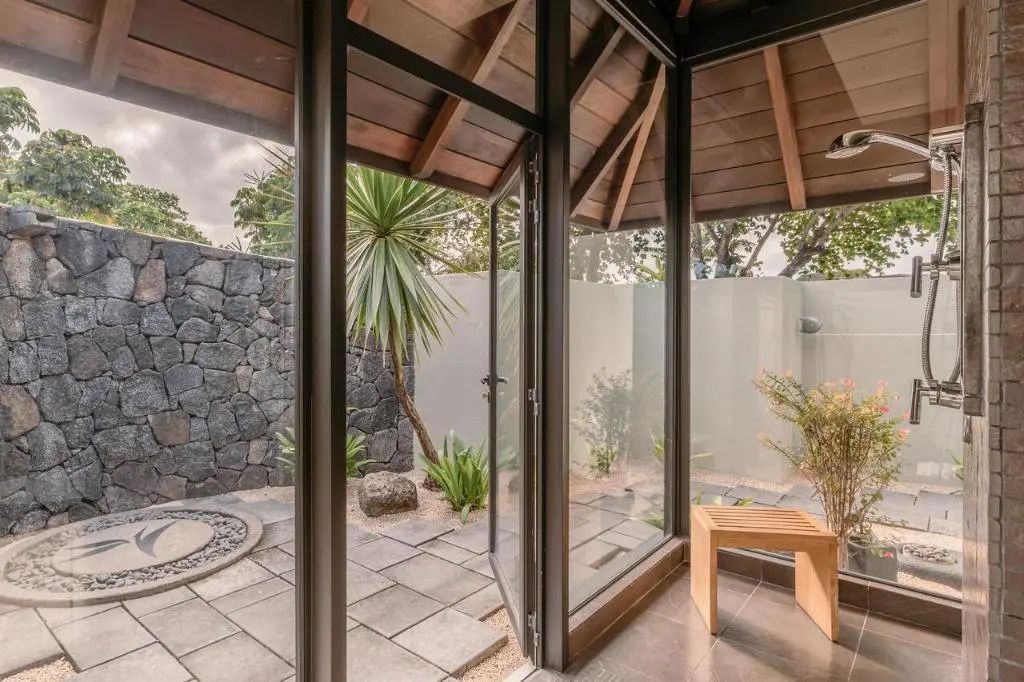 Privater Gartenbereich mit Glaswänden und Natursteinelementen.