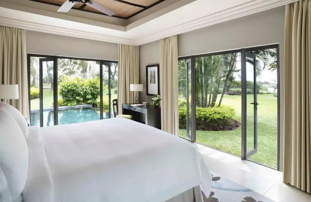 Helles Schlafzimmer mit Blick auf einen privaten Garten und kleinen Pool