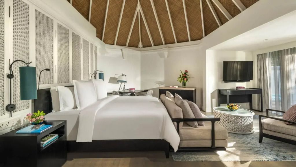 Geräumiges Schlafzimmer mit Doppelbett und gemütlicher Sitzecke im Tropenstil